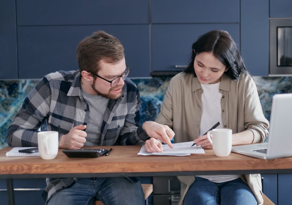 Interracial couple discussing bills and financial planning in a cozy indoor setting.